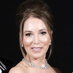 A woman wearing a necklace, smiling, in a formal setting.