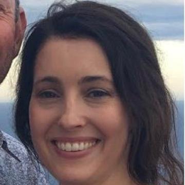 A person smiling with a blurred background.