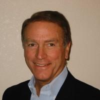 A person wearing a suit jacket and smiling at the camera.