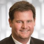 A man in a suit smiling.