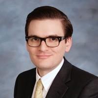 A man in a suit and tie with glasses.