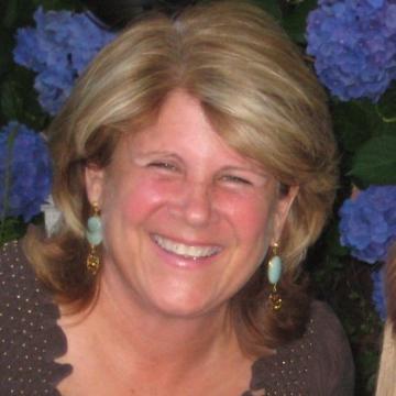 A person smiling with blue flowers in the background.