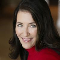 A person smiling, wearing a red top.