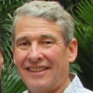 A smiling person in front of greenery.