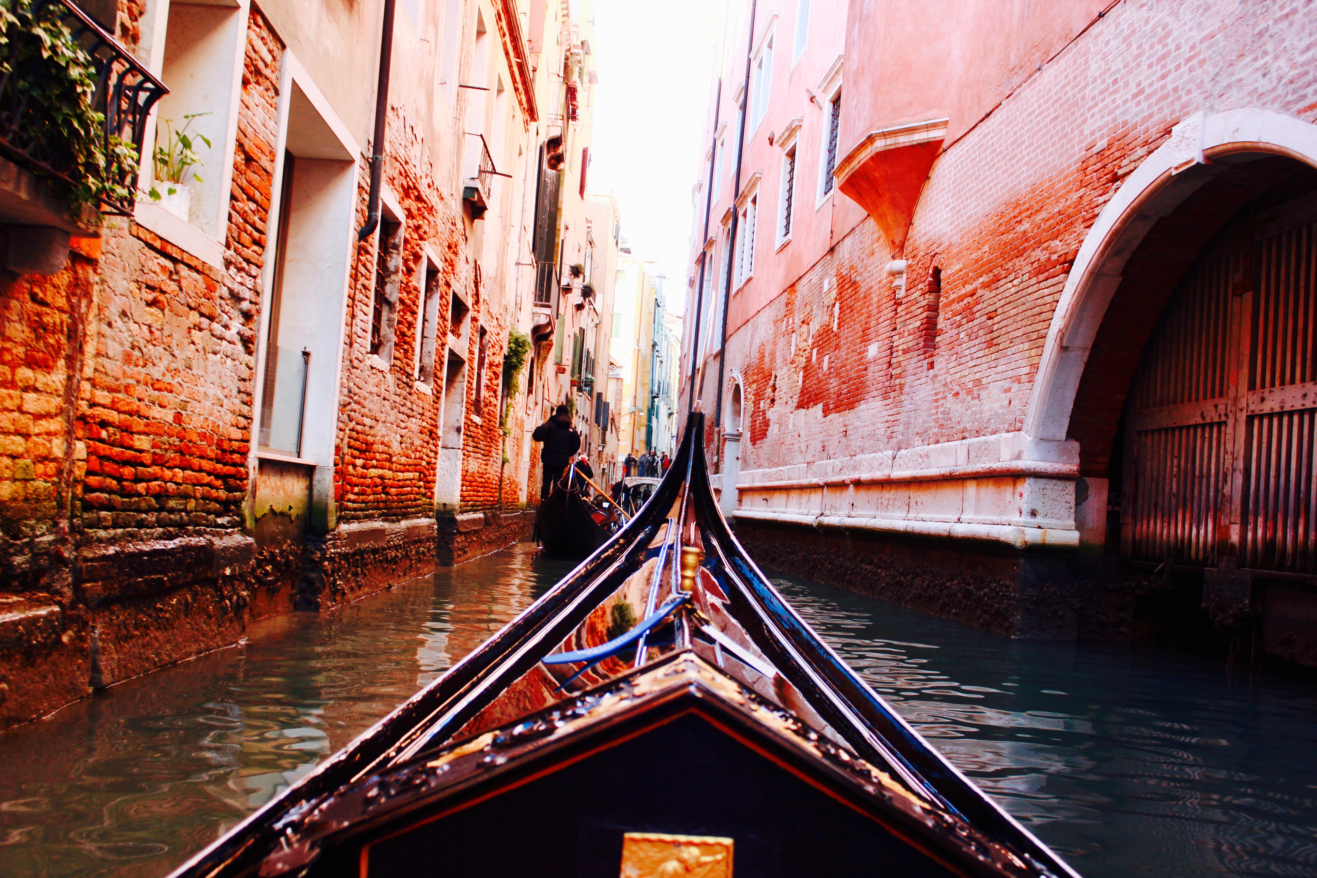 View from gondola in narrow Venetian canal with colorful buildings.