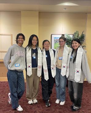 Five students gathered wearing Study Abroad graduation sashes