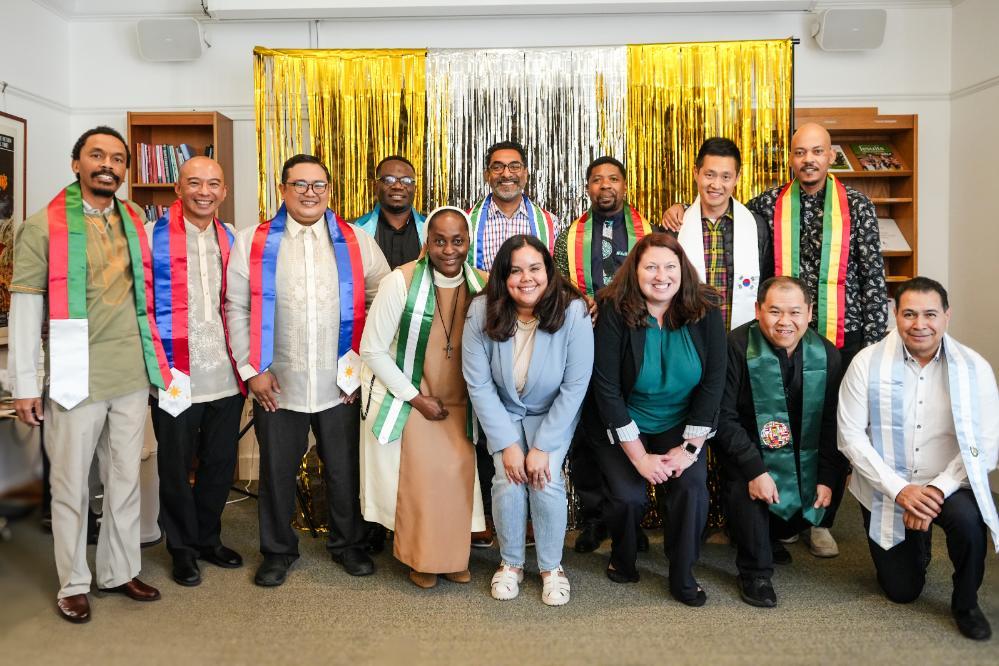 Decorative; students wearing graduation stoles and smiling in front of a backdrop