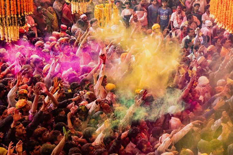 People celebrating Holi with colorful powders in a crowded street.