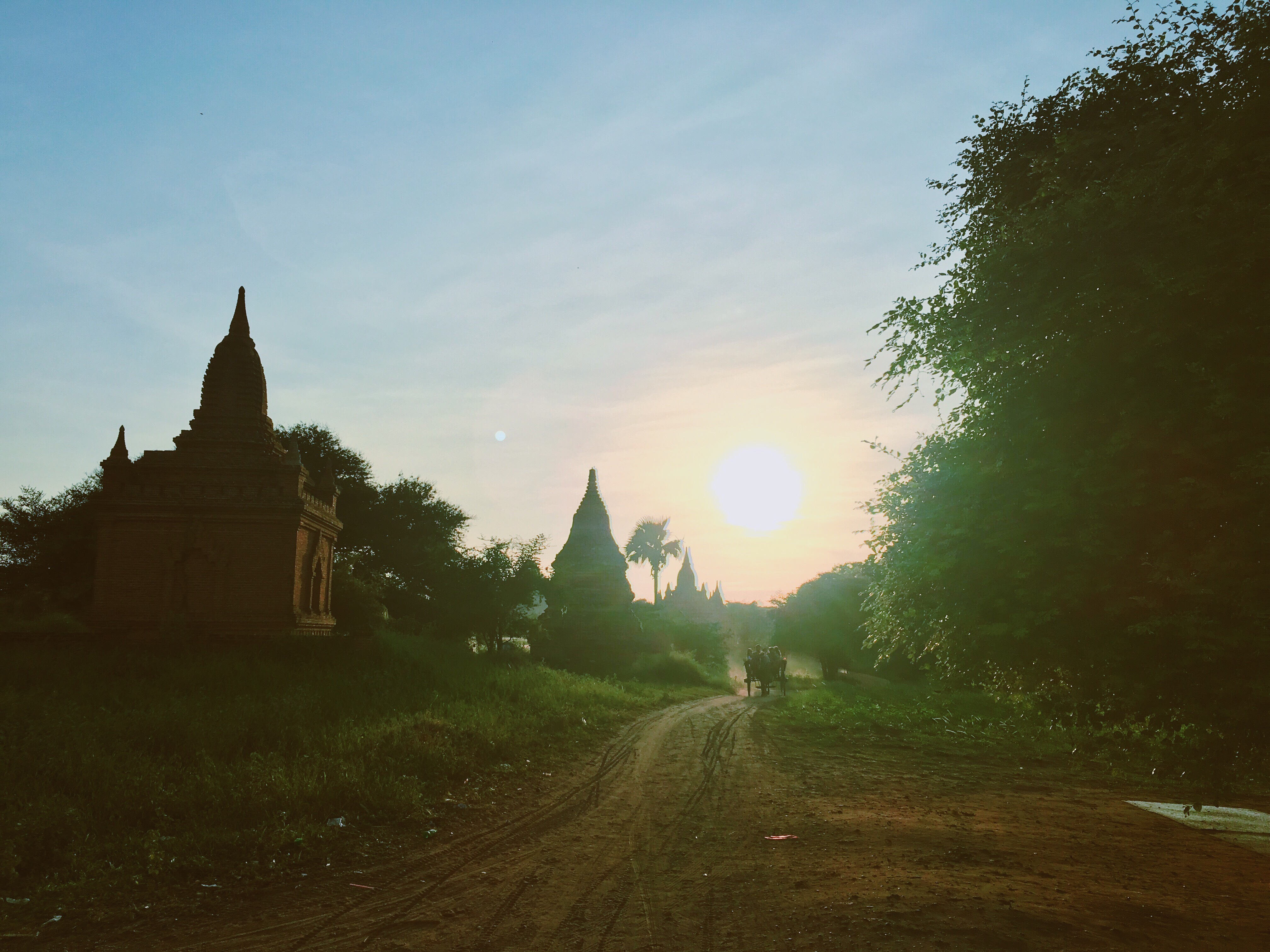 Sunset scene with ancient temples and trees along a trail in Bagan.