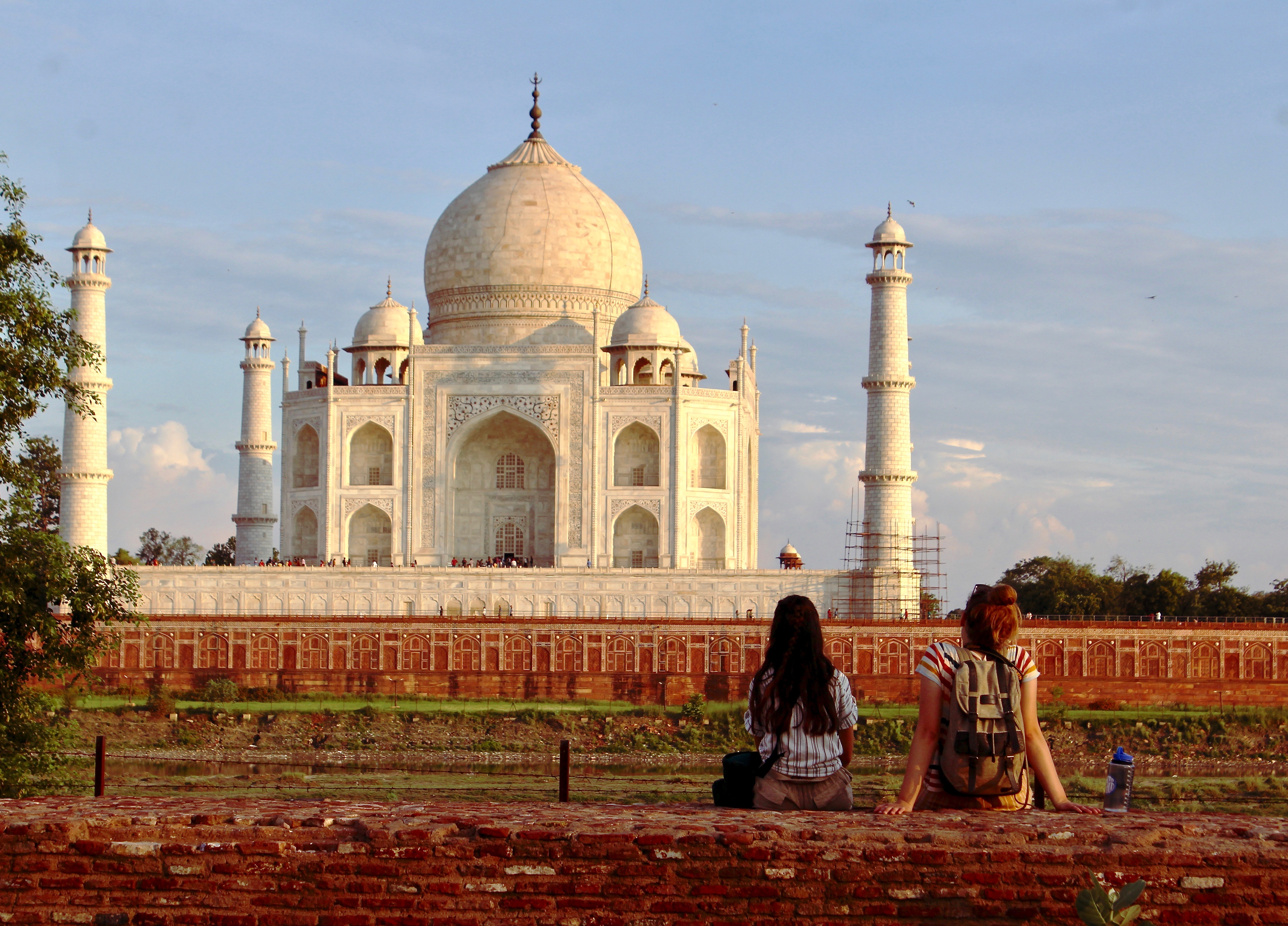 Two people sitting with Taj Mahal in the background.