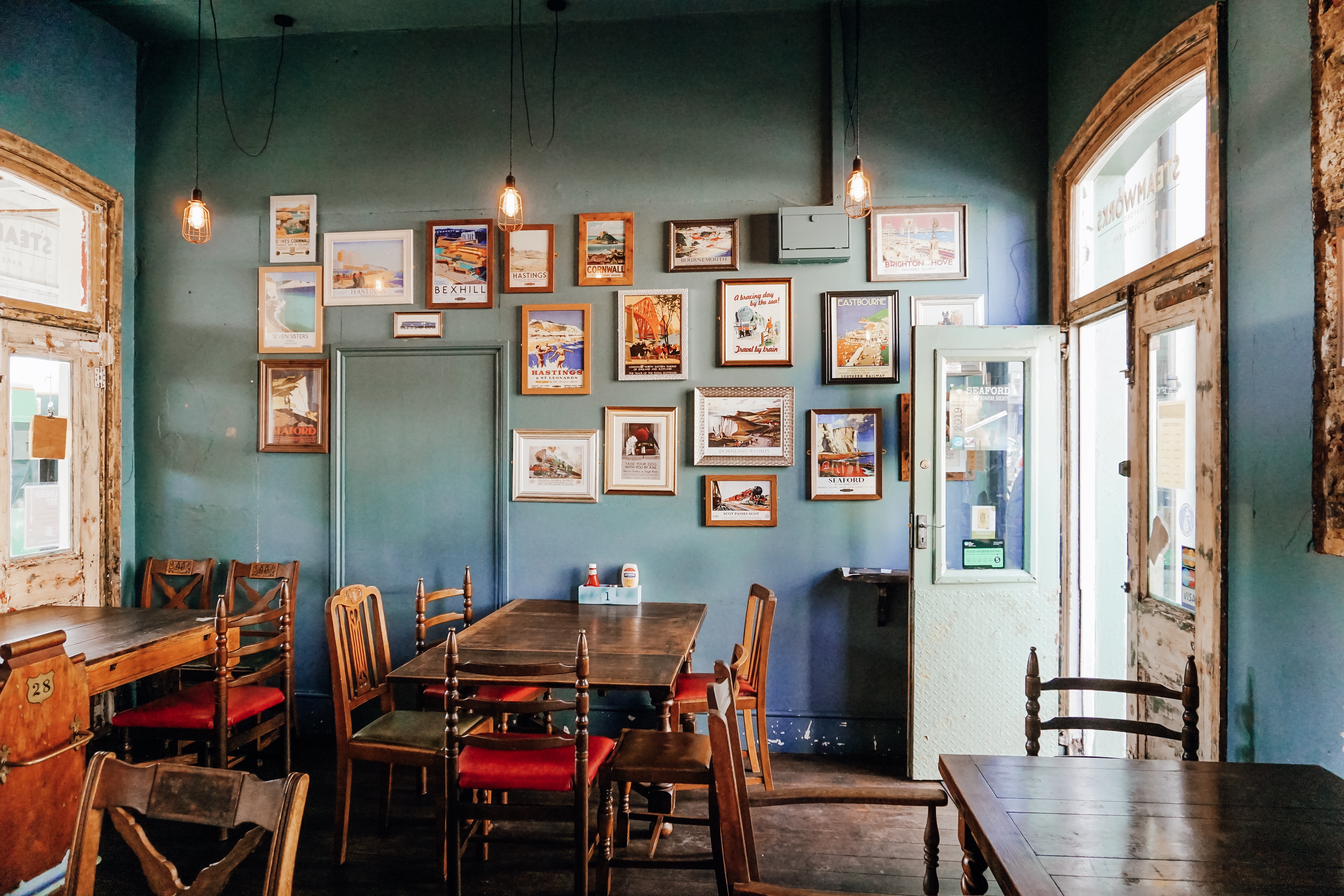 A cozy cafe with teal walls, tables, and framed photos.