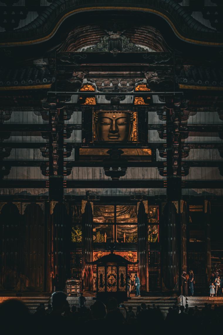 Todai-ji Temple in Nara, Japan; large open window displaying a Buddah head overlooking a crowd of people at night
