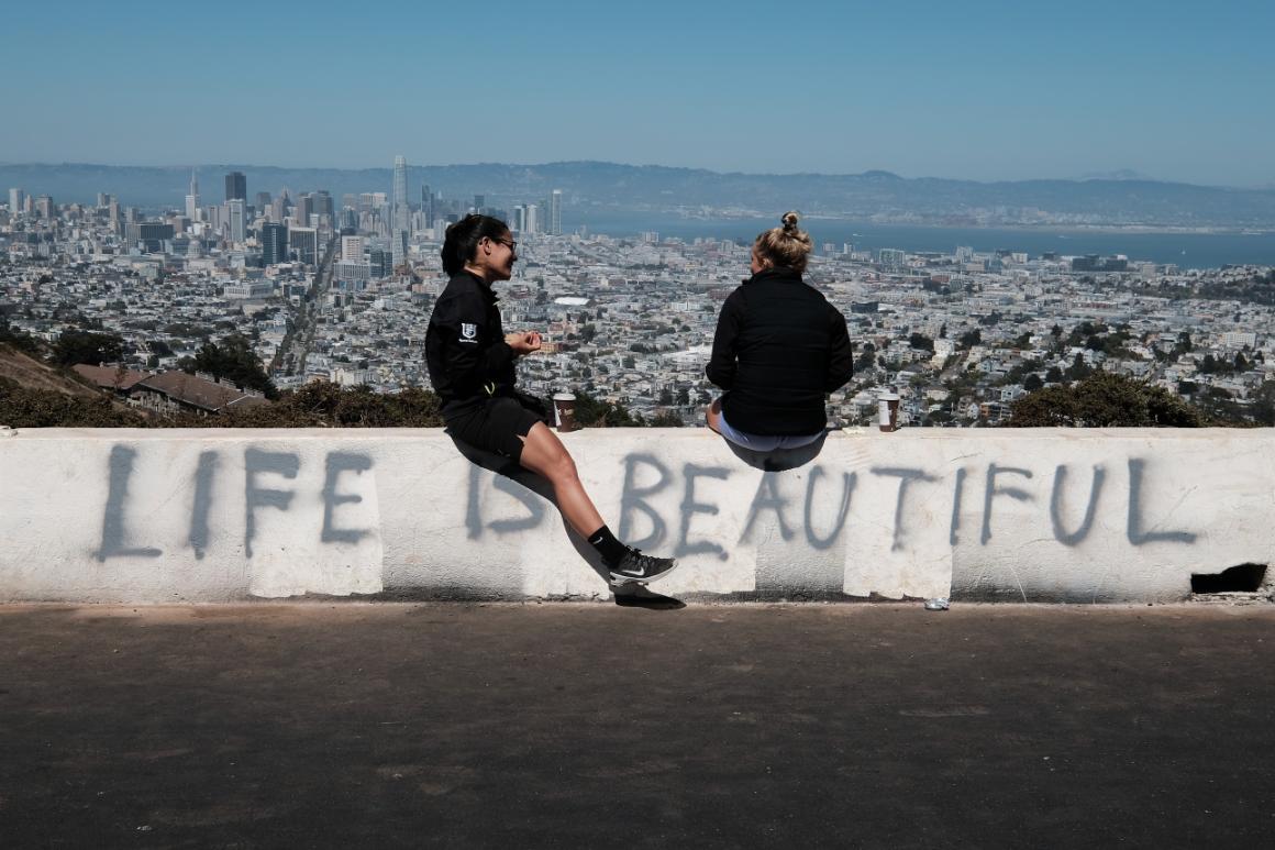 Photo of two people sitting on a barrier with the words 