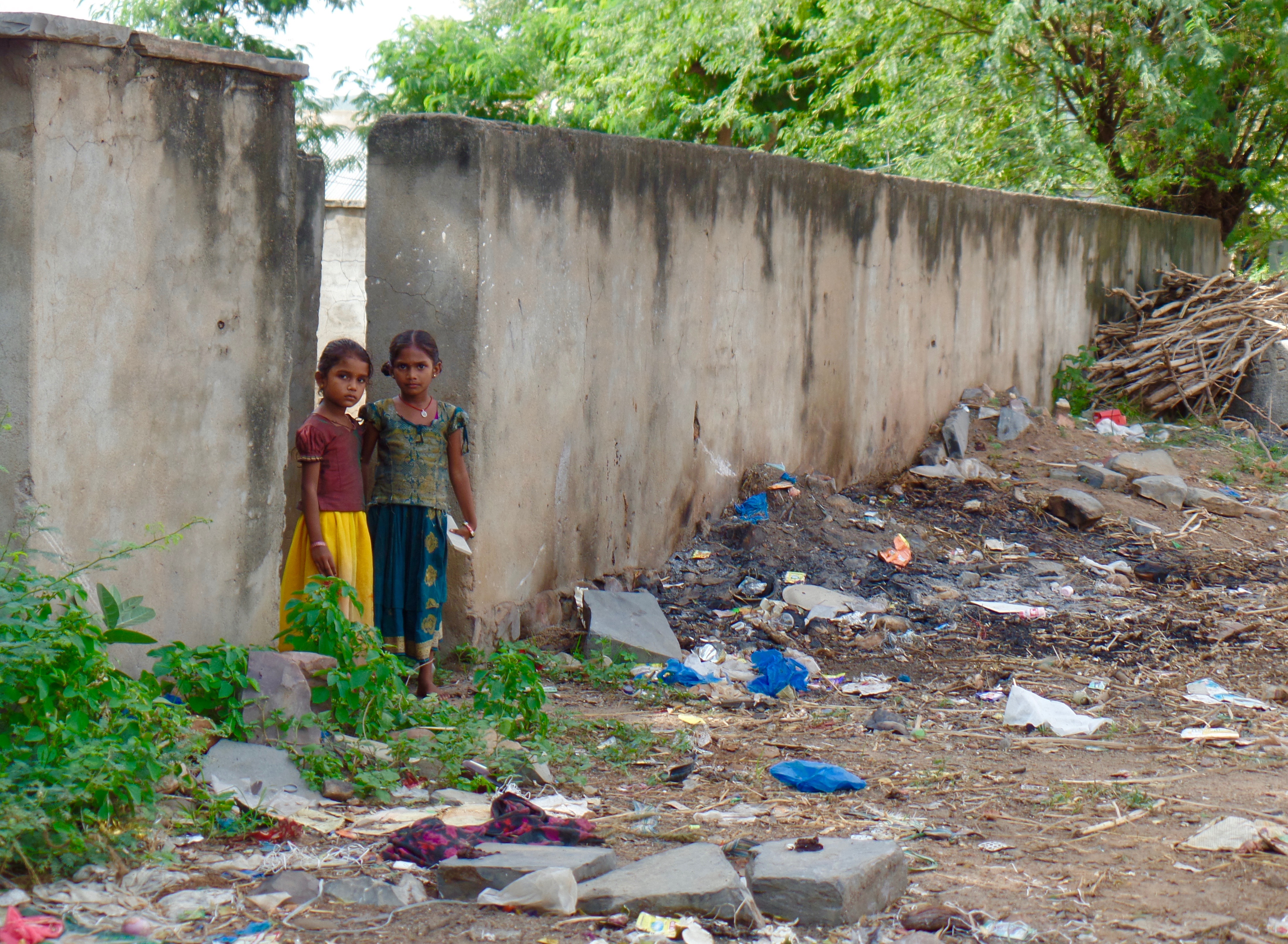 A child peeks through a gap in a concrete wall.
