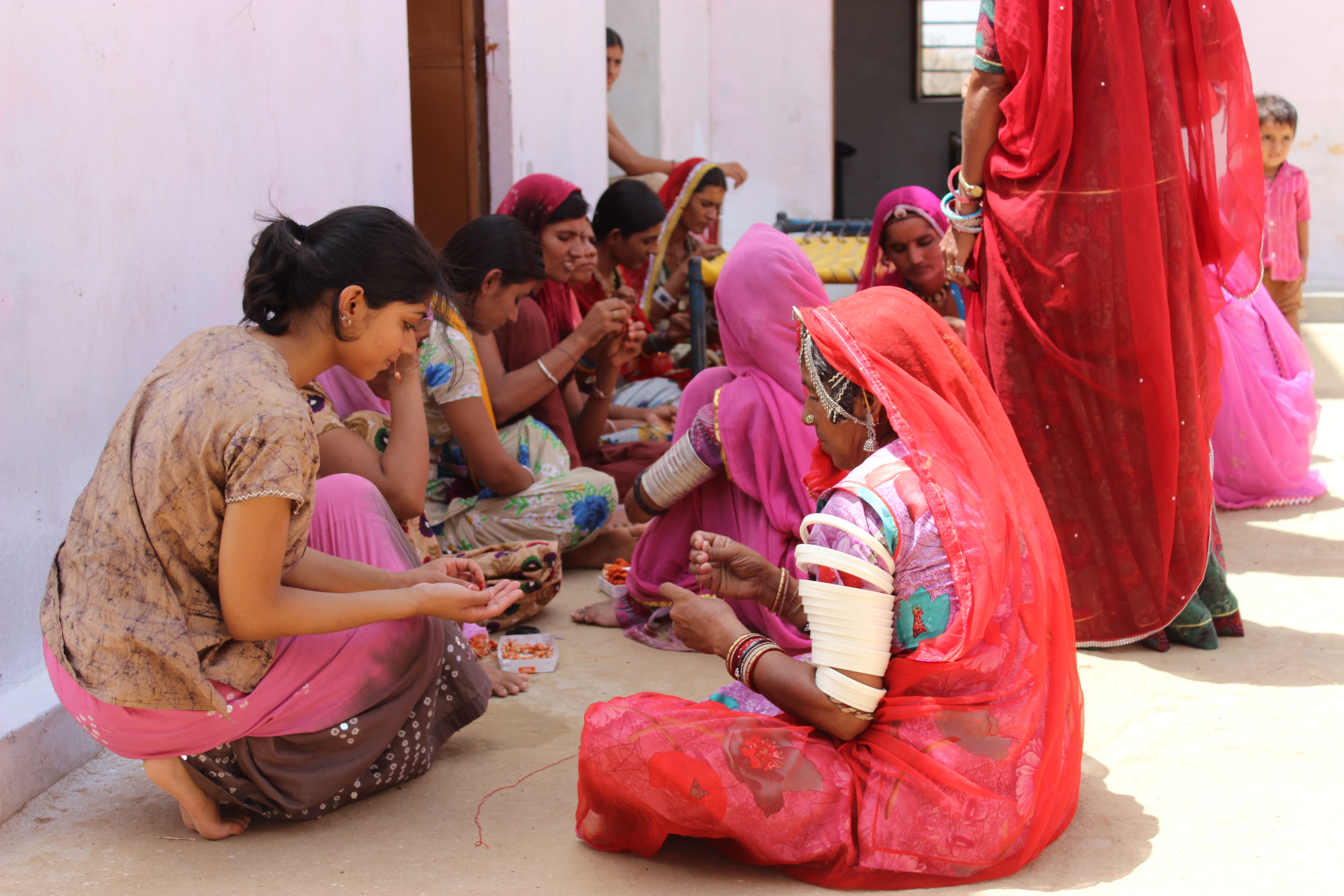 Women in colorful attire sharing food and conversation outdoors.