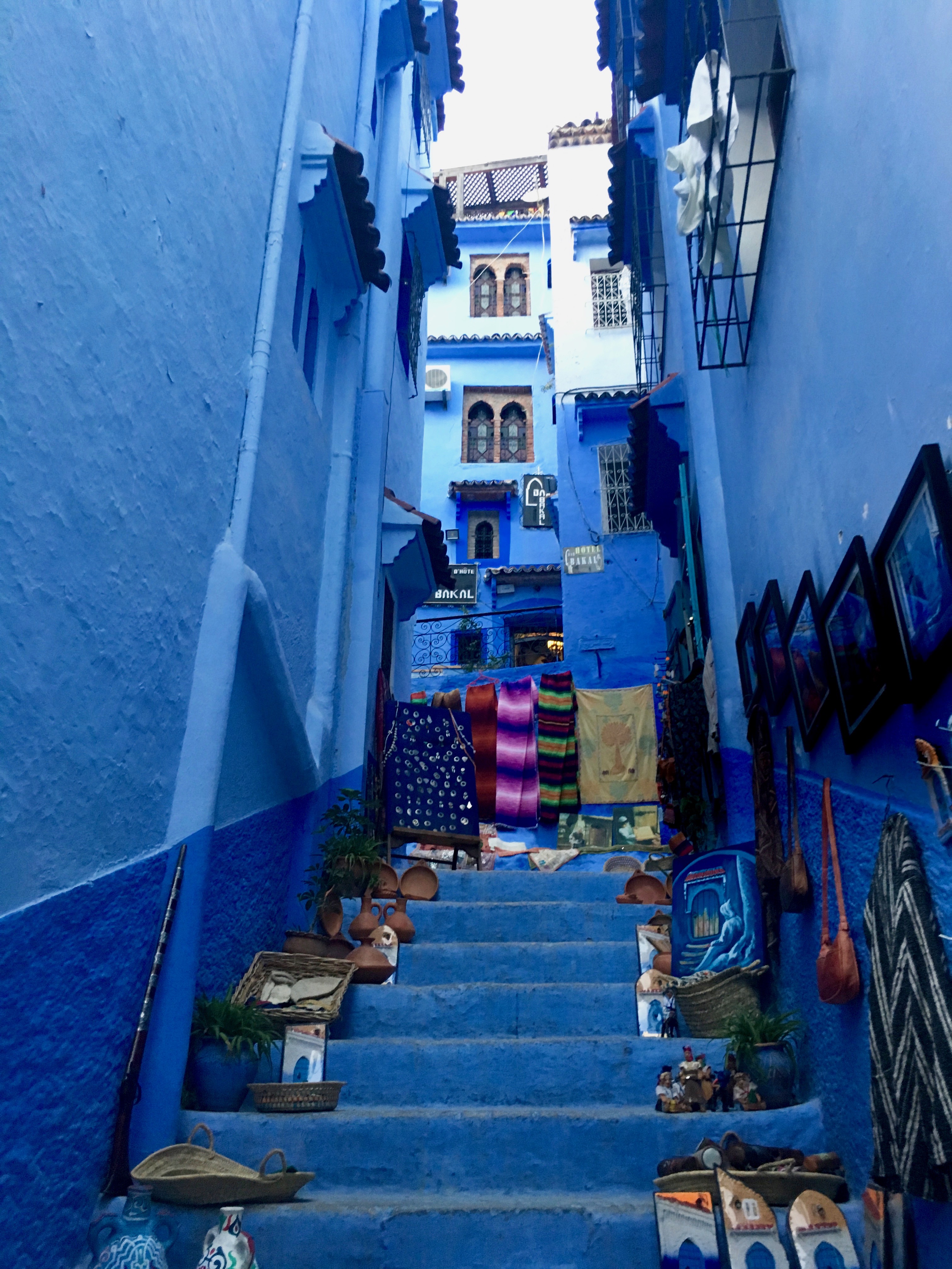 Alt text: Narrow blue alley with colorful plant pots in Chefchaouen.