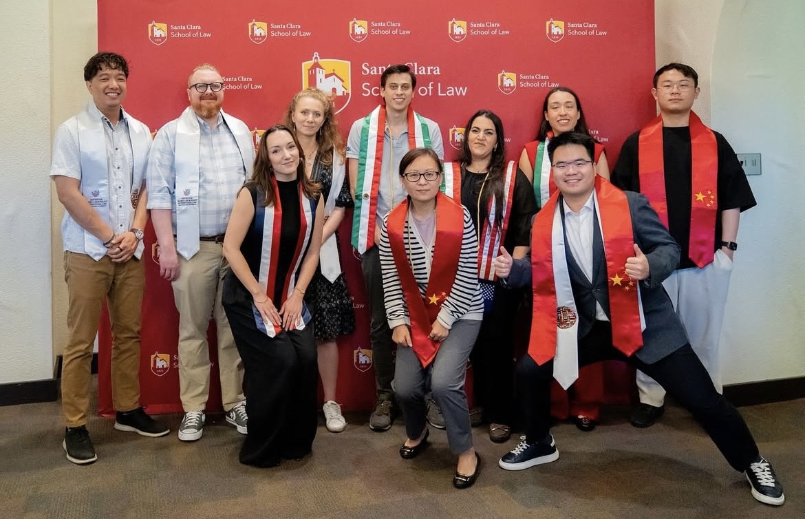 Decorative; students in graduation stoles smiling in front of a backdrop