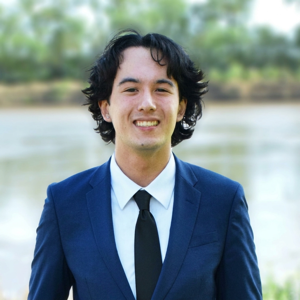 A student smiling in a suit and tie