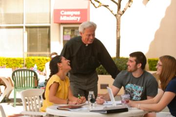 Jesuit with students on Benson patio 