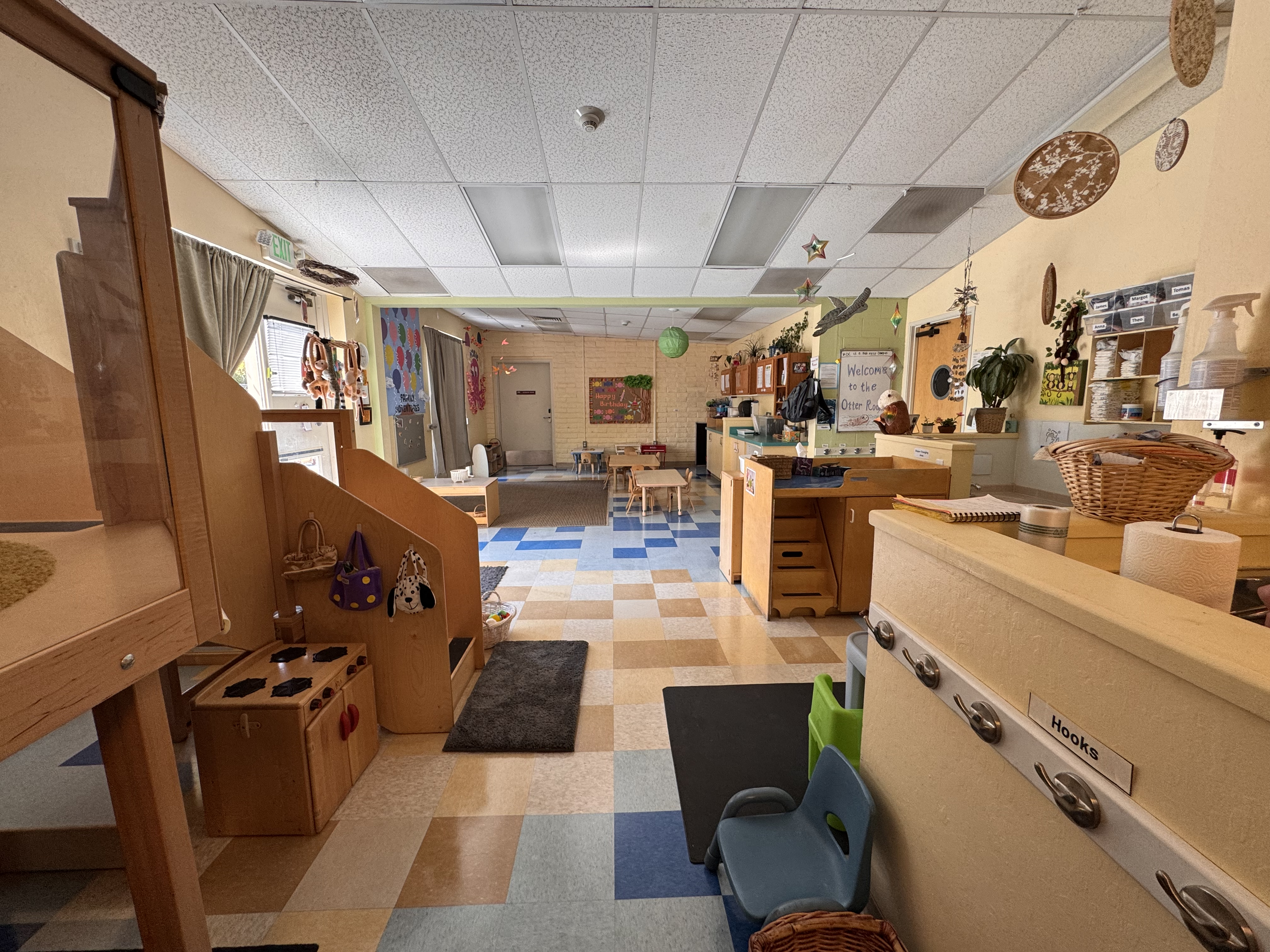 view of the otter classroom from near the entrance to the starfish room, you can see part of the changing table display and part of the jungle gym in the distance you can see the open play area