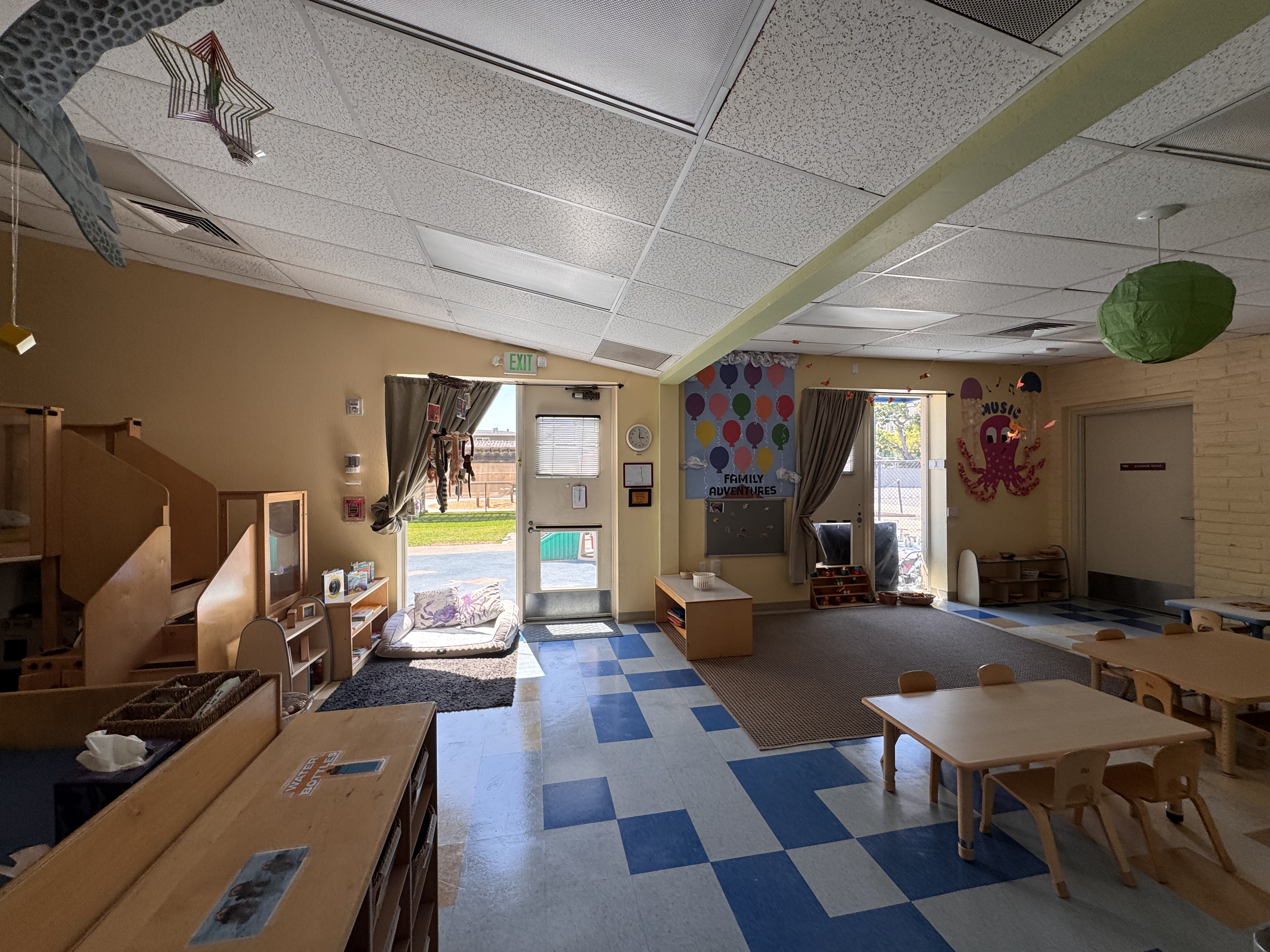 view of the otter room from the entry door, which shows mostly the open play area and play tables with chairs