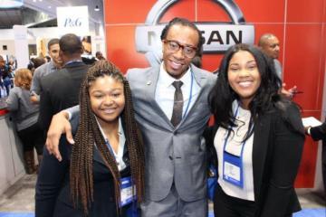 Three people with NSBE badges posing at an event.