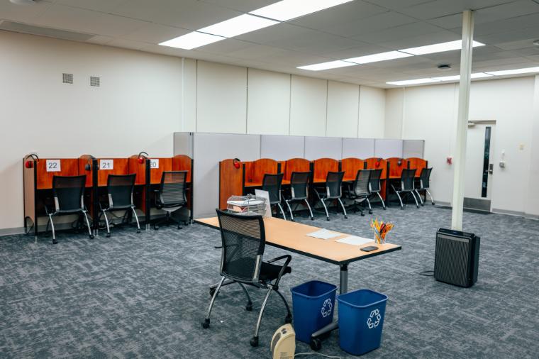 A proctors desk faces a row of study carrels all facing the wall.