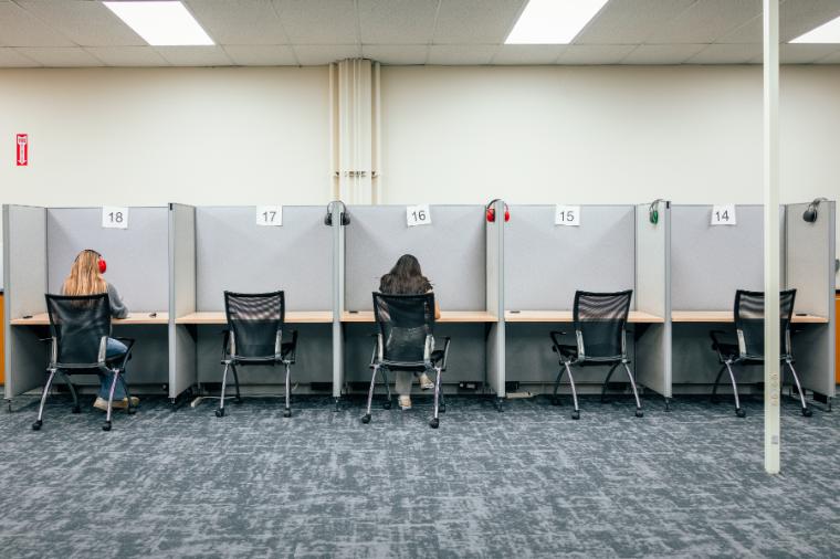 Two students test in study carrels. Noise-canceling headphone are available for each seat.