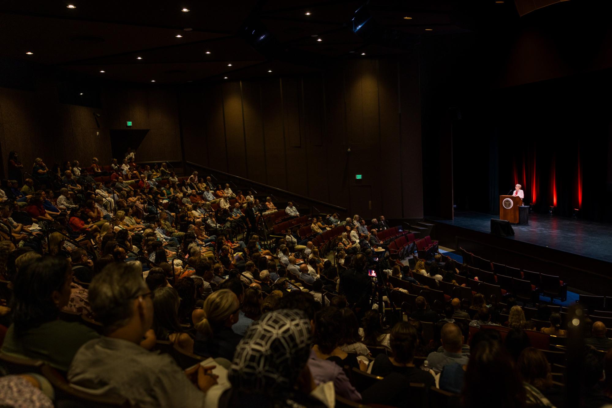 Santa Clara University President Julie Sullivan addresses a full auditorium from the stage during campus convocation.
