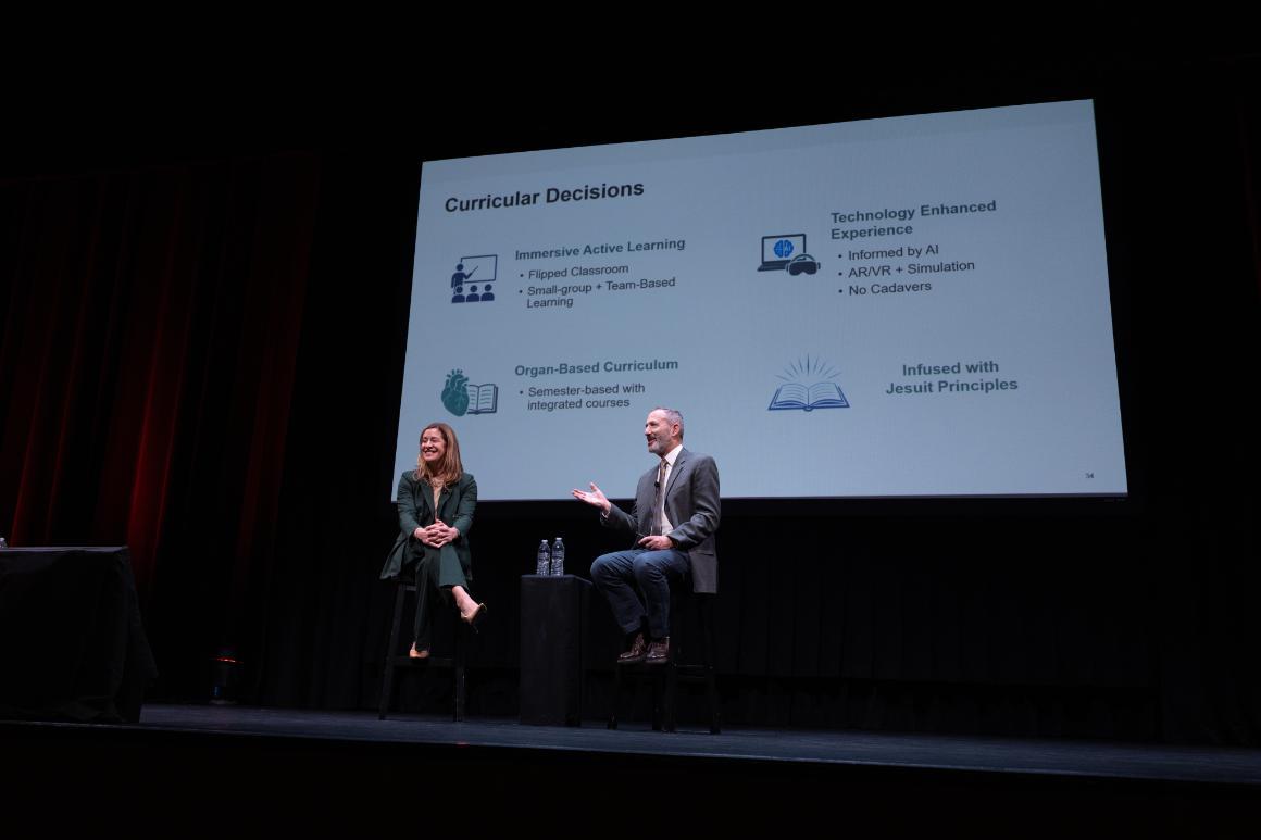 SCU Provost Jim Glaser gestures while speaking beside Lindsay Mazotti, planning dean for the Stevens School of Medicine and chief academic officer at Sutter Health, during a presentation on curricular decisions.