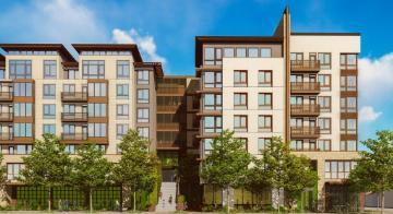 Modern apartment buildings with trees and greenery under a bright blue sky.
