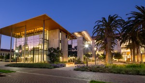 Alt text: Exterior view of Sobrato Campus at dusk with lights and palm trees.