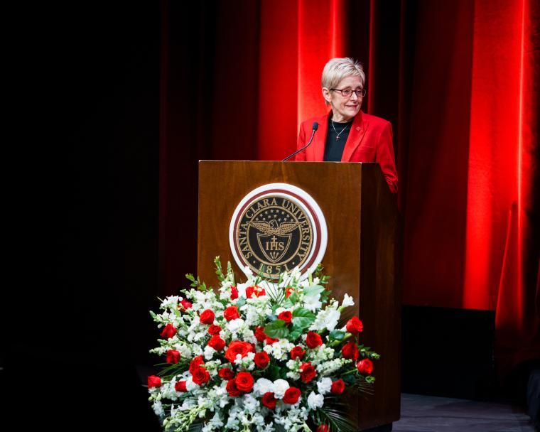 President Julie Sullivan speaking at a podium with roses in the foreground