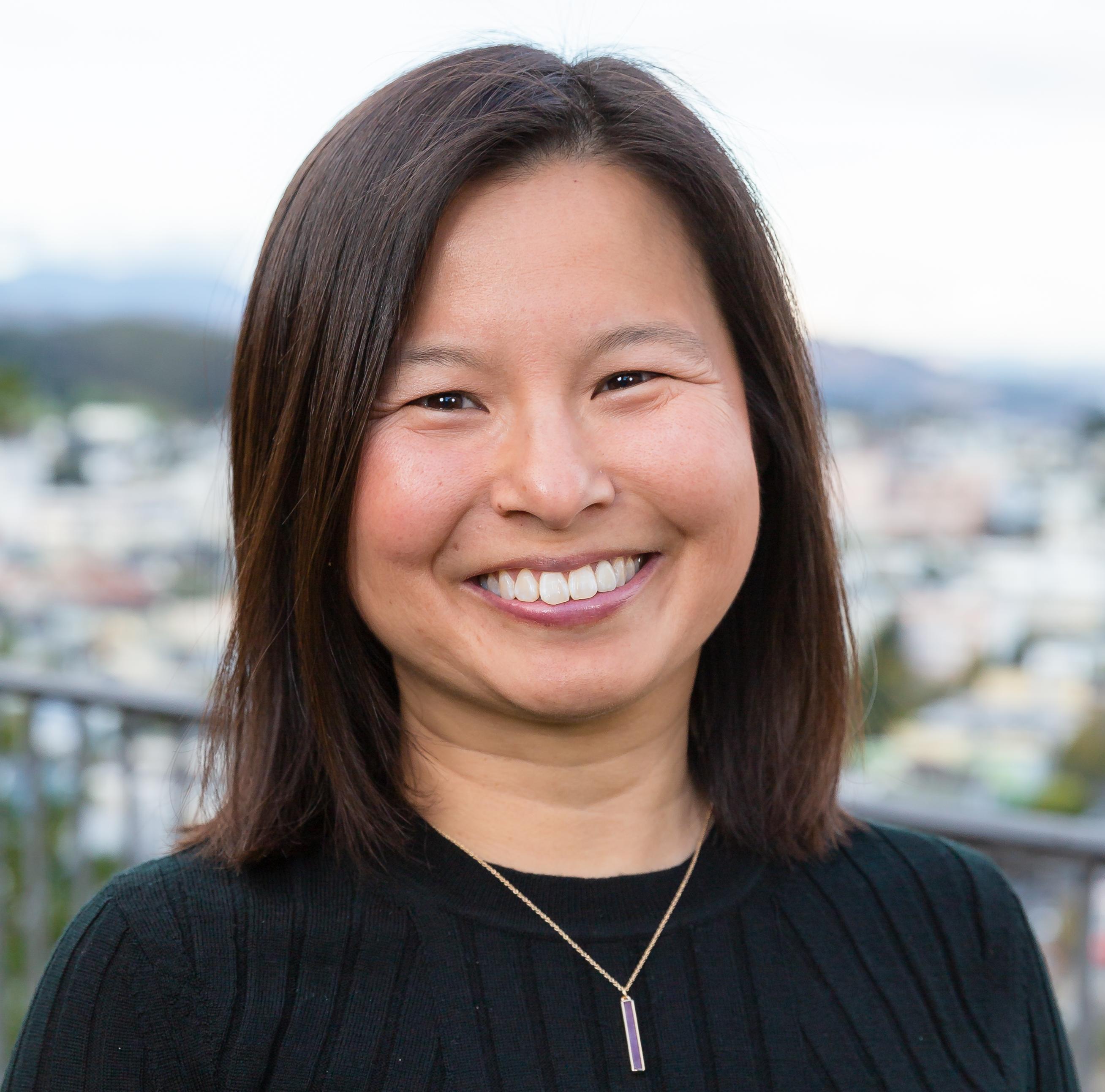 A smiling person with cityscape background.