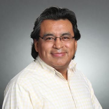 A person smiling in a light-colored shirt.