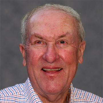 A person smiling against a grey background.