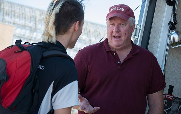 Two people engaged in conversation, one with a backpack.