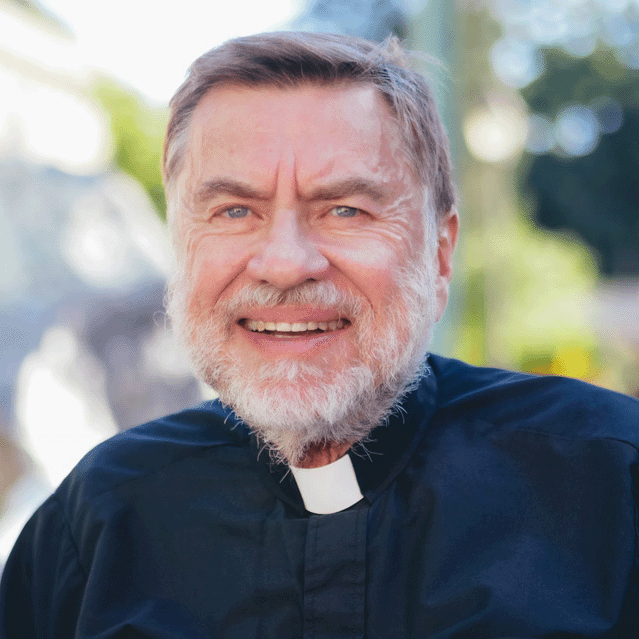 Man in priests collar smiles at camera 