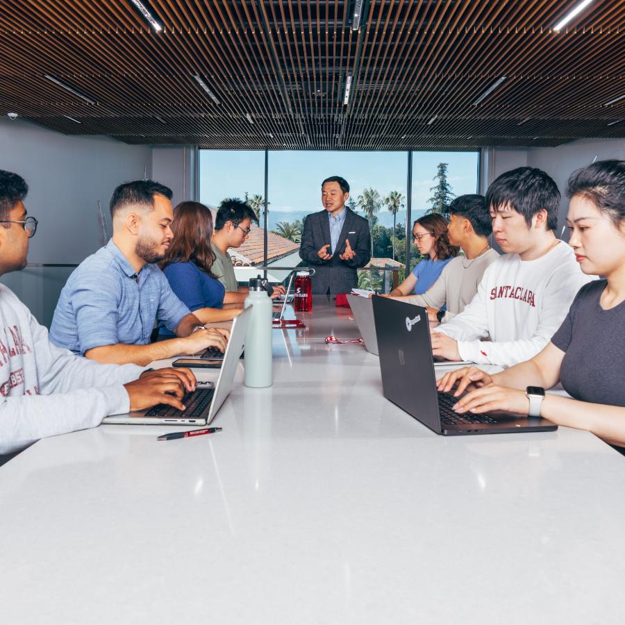 Professor speaks to group of students at computers 