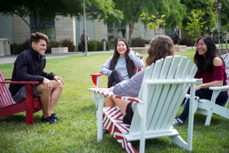 Students sitting in chairs on the lawn smiling. 