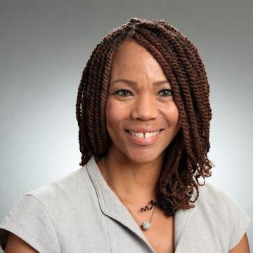 Smiling woman in business attire with a gray background.
