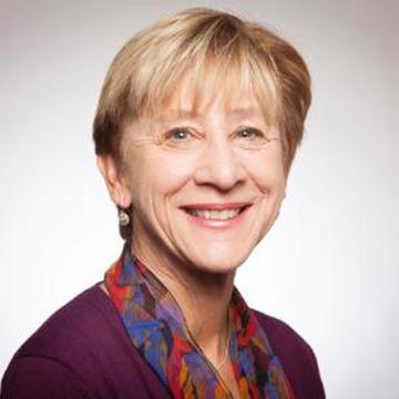 Alt text: Smiling person wearing a scarf with light background. 