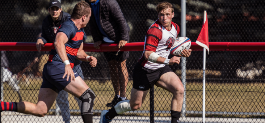 Two rugby players during a match, with one holding the ball.