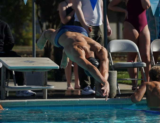 A swimmer dives head first into the pool.