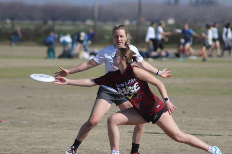 This picture shows a scu player throwing the frisbee around another team who is trying to block her.
