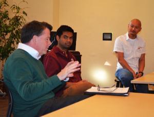 Three people in a meeting with a laptop.