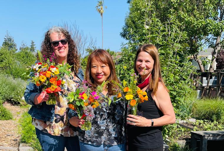 Three people showing their flower arrangements