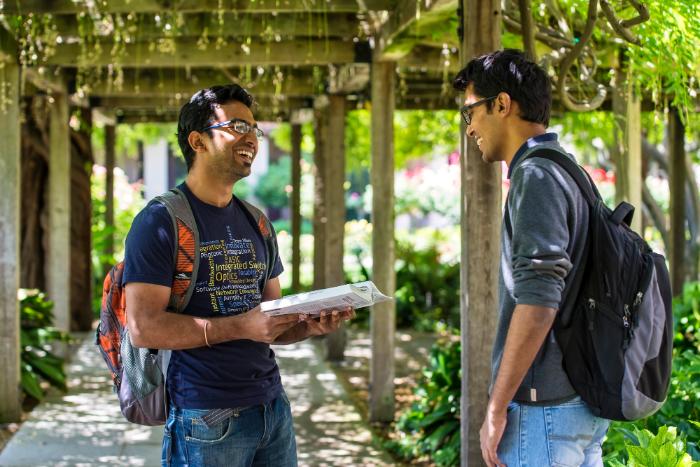 Two students talking under the trellis in the Mission Gardens