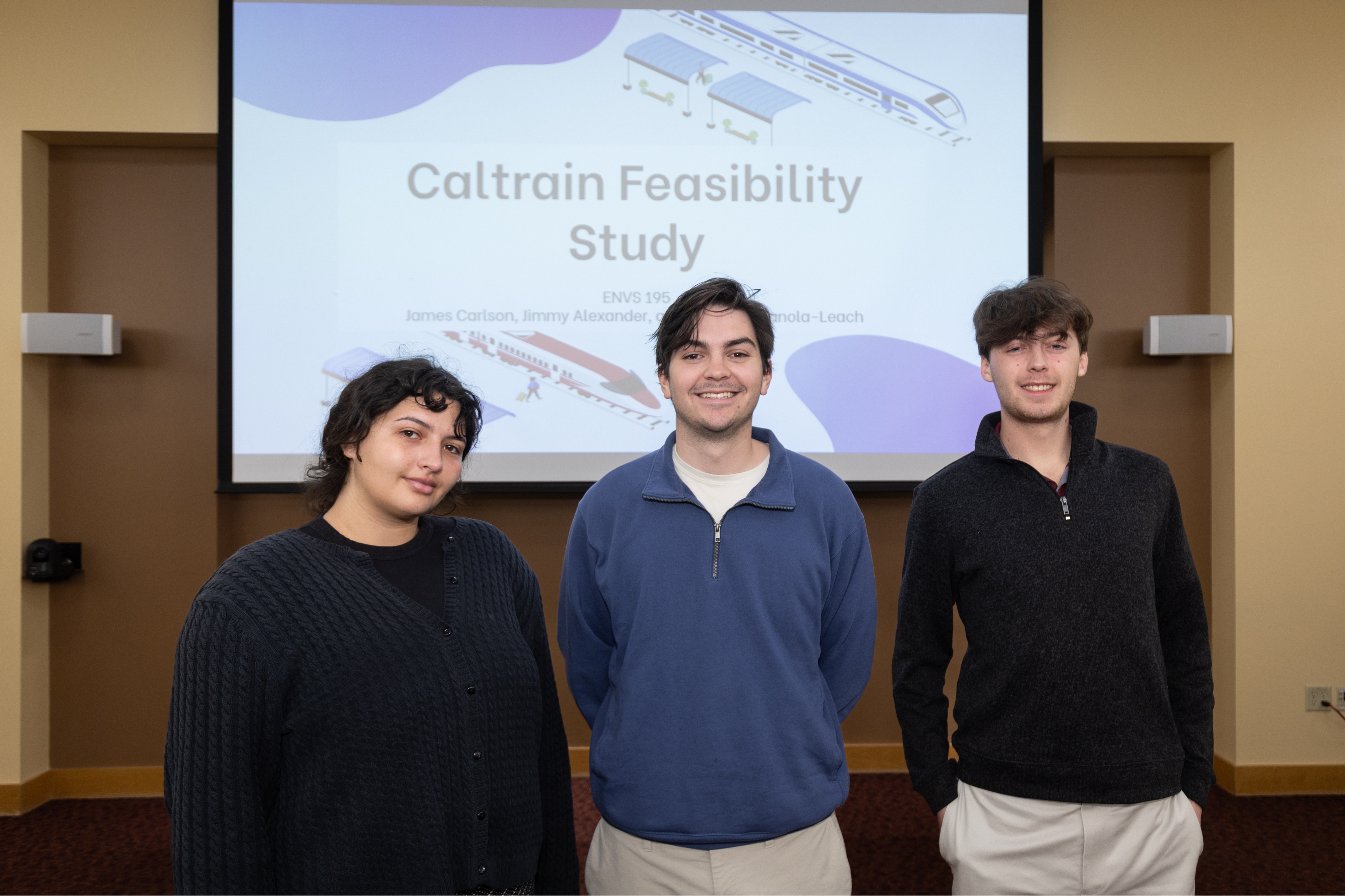 Three students stand in front of their Caltrain Feasibility study presentation during the 2025 Sustainability and EJ Symposium.