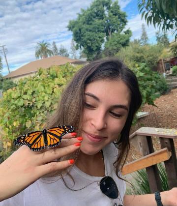 A female student in the Forge garden with a monarch butterfly on her hand.